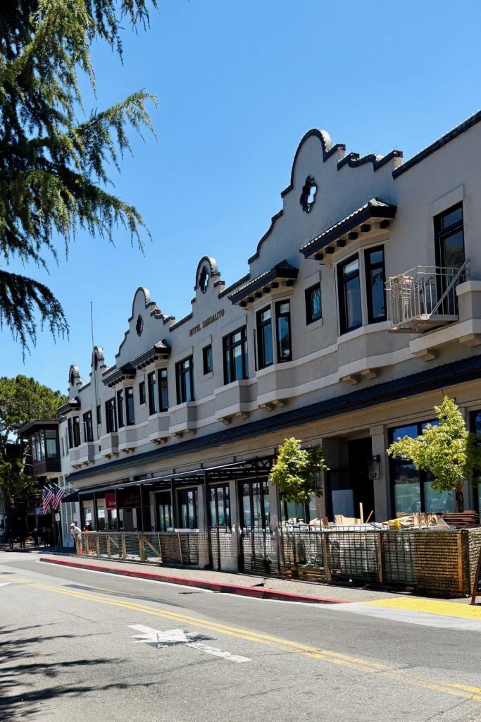 The historic Hotel Sausalito with Spanish-style architecture along a quiet street with sunny blue skies.
