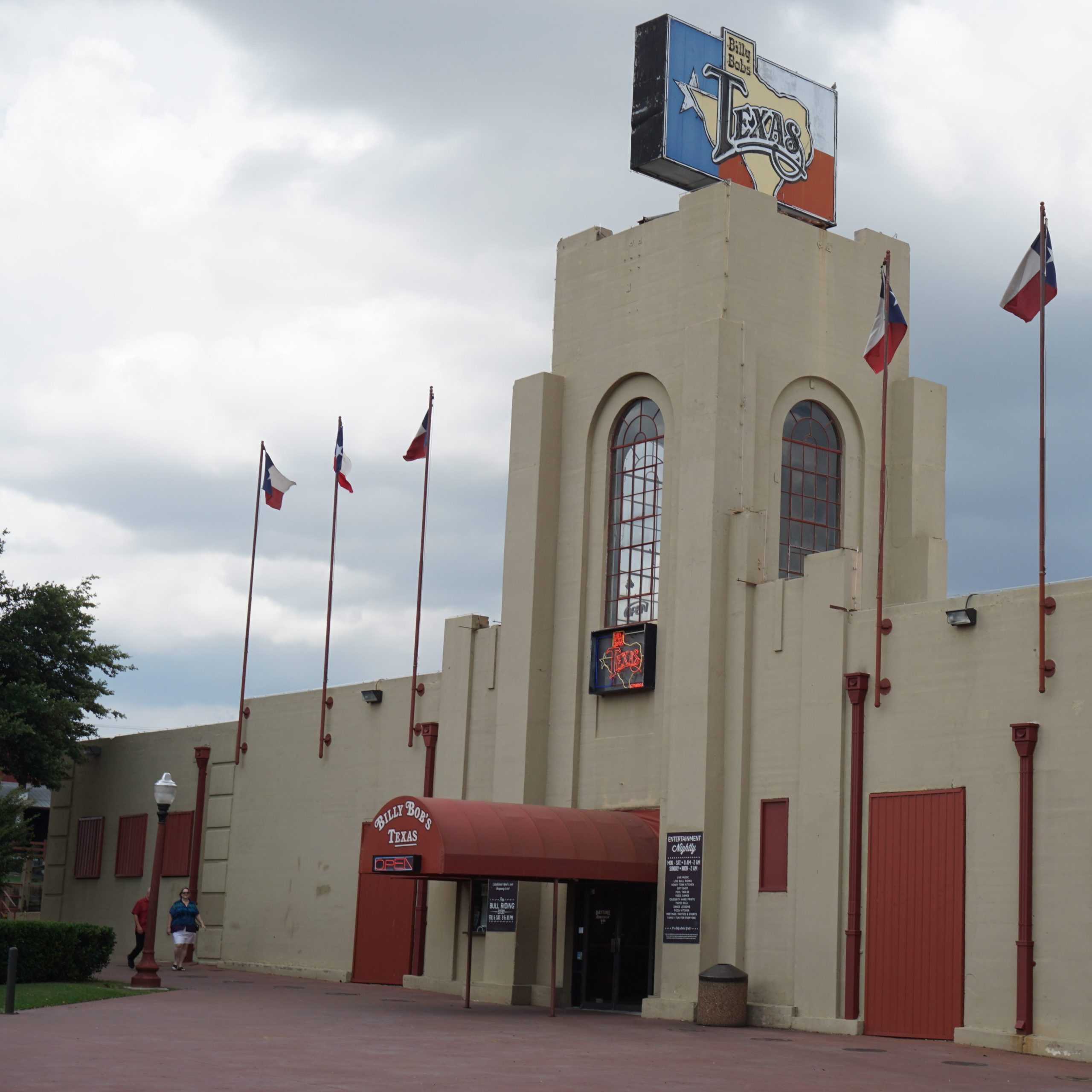 Historic Billy Bob's honky tonk building with tall arched windows and a Texas flag. 